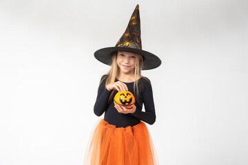 Kids Halloween. A beautiful cute girl in a witch costume, wearing a hat, takes out candy from a basket