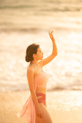 Fototapeta na wymiar Woman in sexy swimwear posing on the tropical beach in sunset light.