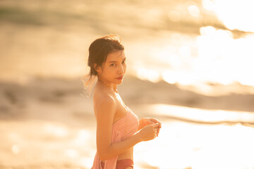 Woman in sexy swimwear posing on the tropical beach in sunset light.