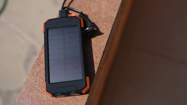 Solar power bank recharging by sunlight outdoor closeup