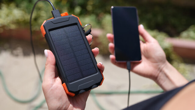 Female hand holding solar power bank and mobile phone closeup