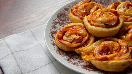 Puff pastry snails, with cheese and ham on a plate