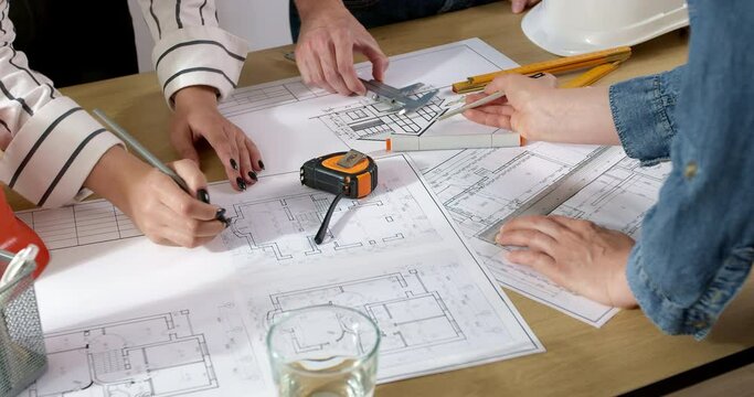 Colleagues architects are working on a construction project. Design drawings on the desktop of builders.