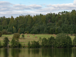 Autumn landscape in the Republic of Karelia, northwest Russia. Lake in calm weather, forest, haystacks on the field