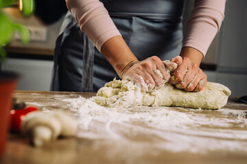 Obraz na płótnie Canvas woman making dough in home kitchen