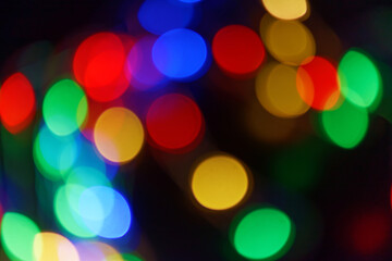 Fototapeta premium Defocused bokeh lights on black background, an abstract naturally blurred backdrop for Christmas eve or birthday party. Festive light texture. Colorful garland in blur. Overlay effect for design. 2023