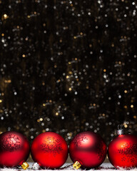 Christmas decorations composition view of four red evening balls with red glitter snowflakes on it on dark background with silver and gold colors bokeh. Holiday concept with copy space on top