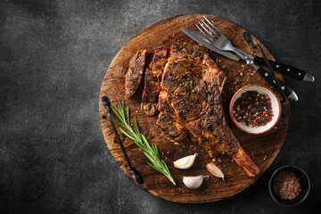 Freshly grilled Tomahawk steak on a wooden cutting board, BBQ food, top view, grey background.