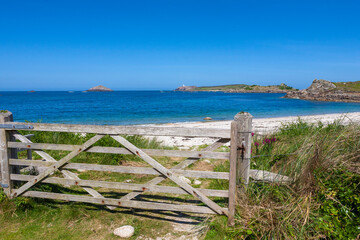 Gimble Porth on the north-east coast of Tresco, Isles of Scilly, UK, with the lighthouse on Round Island visible in the distance