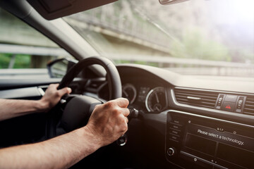 Fototapeta na wymiar Male hands on a car's steering wheel