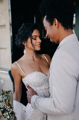 Stylish stunning couple together on their wedding day near the hotel in the city. Wedding fashion outfits.