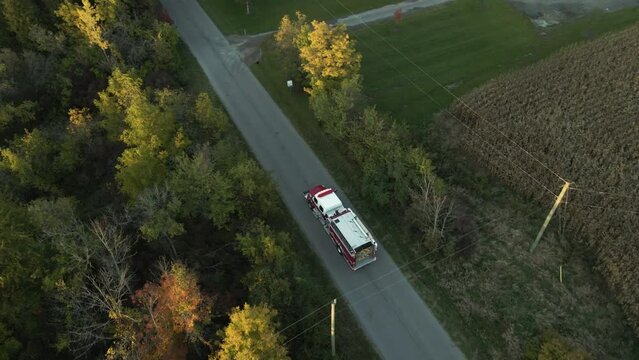 Aerial Tracking View of Emergency Fire Truck Vehicle Driving Fast along Countryside Road with Flashing Lights, Rescue First Responder Mission for Fire Fighting Accident Alert, Route Through Landscape