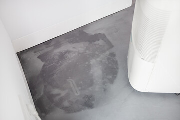 Detail of a damp microcement floor after flooding and a dehumidifier at work