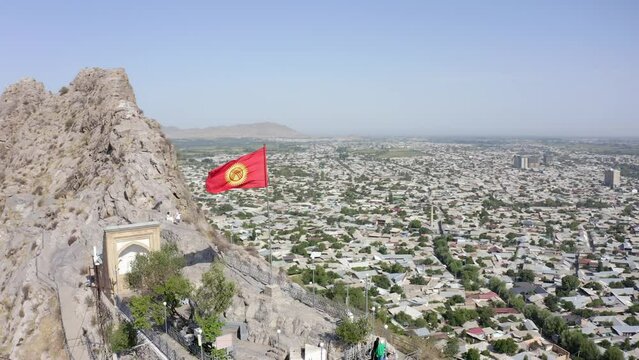 The flag of Kyrgyzstan on Sulaiman-Too is a rocky sacred mountain and a symbol of the city of Osh. View of the city of Osh from a height, Kyrgyzstan.