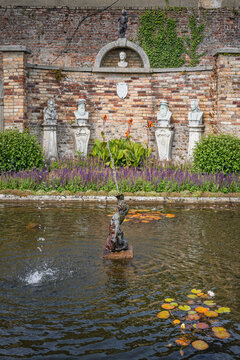 Triton statue and fountain on a small pond with bust statues in Powerscourt gardens, Enniskerry, Wicklow, Ireland
