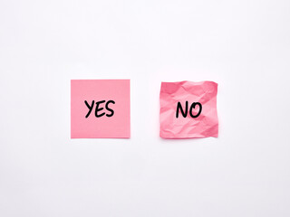 The words yes and no on pink sheets of note paper. Say or choose yes