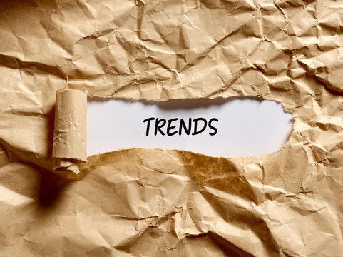 The Word Trends Written Under A Brown Torn Paper. Discovering The Current Popular Trends