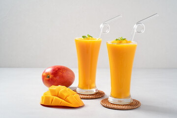 Fresh beautiful delicious mango juice smoothie in glass cup on gray table background.