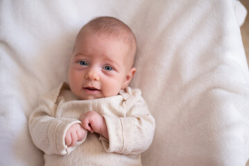 Newborn in white overall lies in child seat on white blanket. Kid in white t-shirt with surprise face. Childs - happiness for family. New worries and lifestyle. close up 