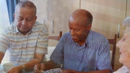 Animation of flag of usa over senior diverse people playing cards - Powered by Adobe