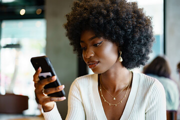 Fototapeta na wymiar Young woman using mobile phone at coffee shop