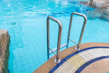 Ladder stainless handrails for descent into swimming pool. Swimming pool with handrail . Ladder of a swimming pool. Horizontal shot. stairs swimming pool. Stainless steel ladder