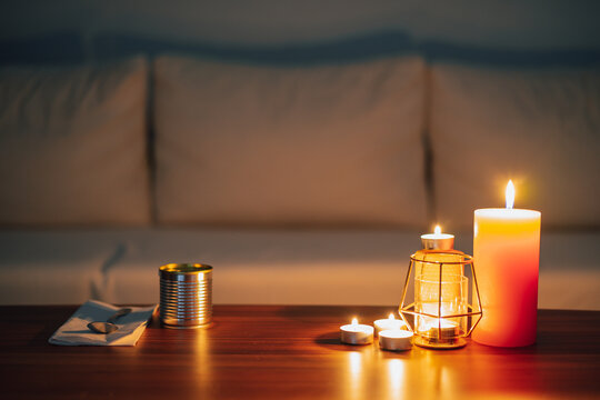 Power Cut, Lit Candles In A Dark Living Room And Canned Food Ready To Eat