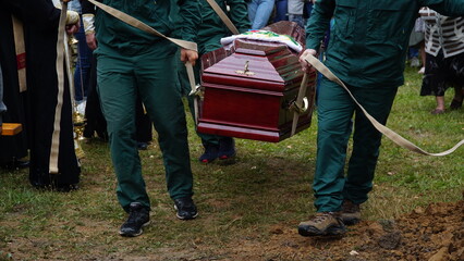 Burial. Men lower the coffin into the grave. n