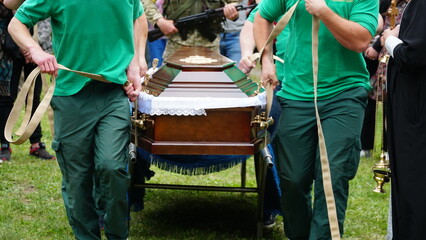 Burial. Men lower the coffin into the grave. n