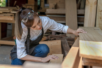 Fototapeta na wymiar Young Asian carpenter woman working with wood project in carpentry workshop, Carpenter concept