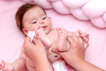 Newborn baby getting a diaper change: mom wiping baby's bottom with baby wipe. emotions of newborn baby - obrazy, fototapety, plakaty