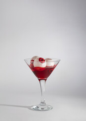 Halloween concept idea. Martini glass with red drink and spooky eyes in it. Creepy party cocktail abstract design. Horror holiday idea