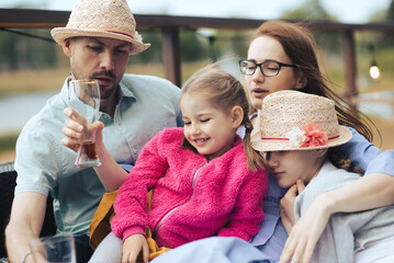 Obraz premium happy young family- mom,dad and two children teenage girl and little daughter traveling together and relaxing in street cafe