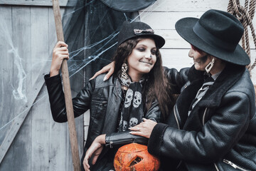 Fototapeta na wymiar Scary family,mother,daughter celebrating halloween. Street barn. Pumpkin jack-o-lantern.Terrifying black skull half-face makeup and witch costumes, broom,stylish images hat, jackets. Children's party