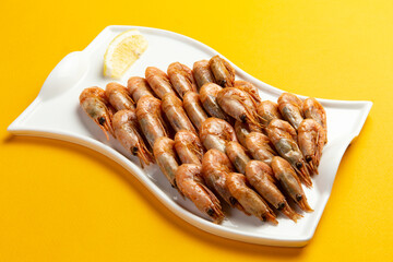 Fried shrimp in a plate on a yellow background.