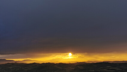 hdr Il sole al tramonto illumina le montagne in un cielo di nuvole nere