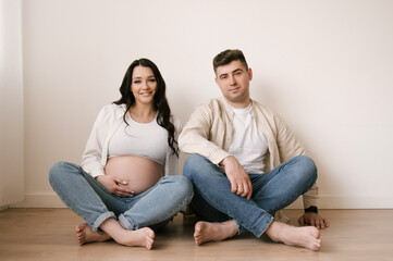 Young pregnant woman with husband at home, happy family and pregnancy concept