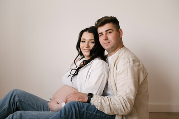 Young pregnant woman with husband at home, happy family and pregnancy concept