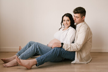 Fototapeta na wymiar Young pregnant woman with husband at home, happy family and pregnancy concept