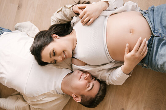 Young pregnant woman with husband at home, happy family and pregnancy concept
