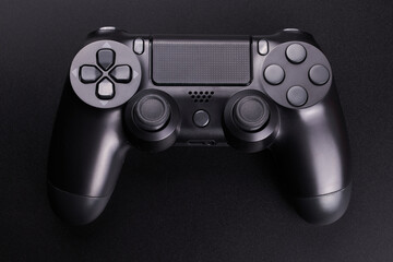 Black video game controller, joystick for game console isolated on black background. Gamer control device close-up