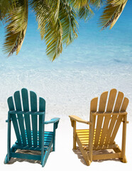 Beach chairs under palm branch in Aruba.. Soft wave of turquoise ocean water