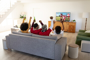 African american family supporting and watching tv with football match on screen