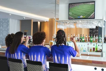 Foto op Aluminium Diverse friends supporting and watching tv in bar with football match on screen © vectorfusionart
