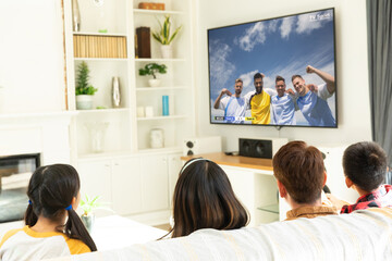 Diverse children watching tv with football match on screen