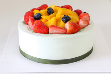 Deliciously creamy birthday cake, fruit cake, filled with fresh strawberries, blueberries and mango