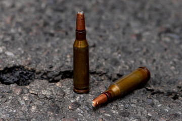 Cartridges with bullets with a displaced center of gravity against the background of cracked asphalt, selective focus, homemade expansive bullets. Concept: heavy damage, prohibited ammunition, war.