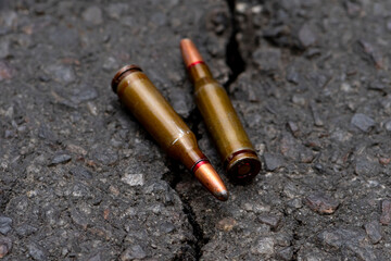 Cartridges with bullets with an offset center lie on cracked asphalt, selective focus, homemade expansive bullets. Concept:prohibited ammunition, the war in Ukraine.