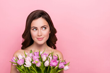 Photo of sweet dreamy young woman naked shoulders holding flowers blossom looking empty space isolated pink color background