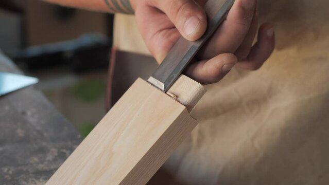 woodworker with chisel makes mortise and tenon 